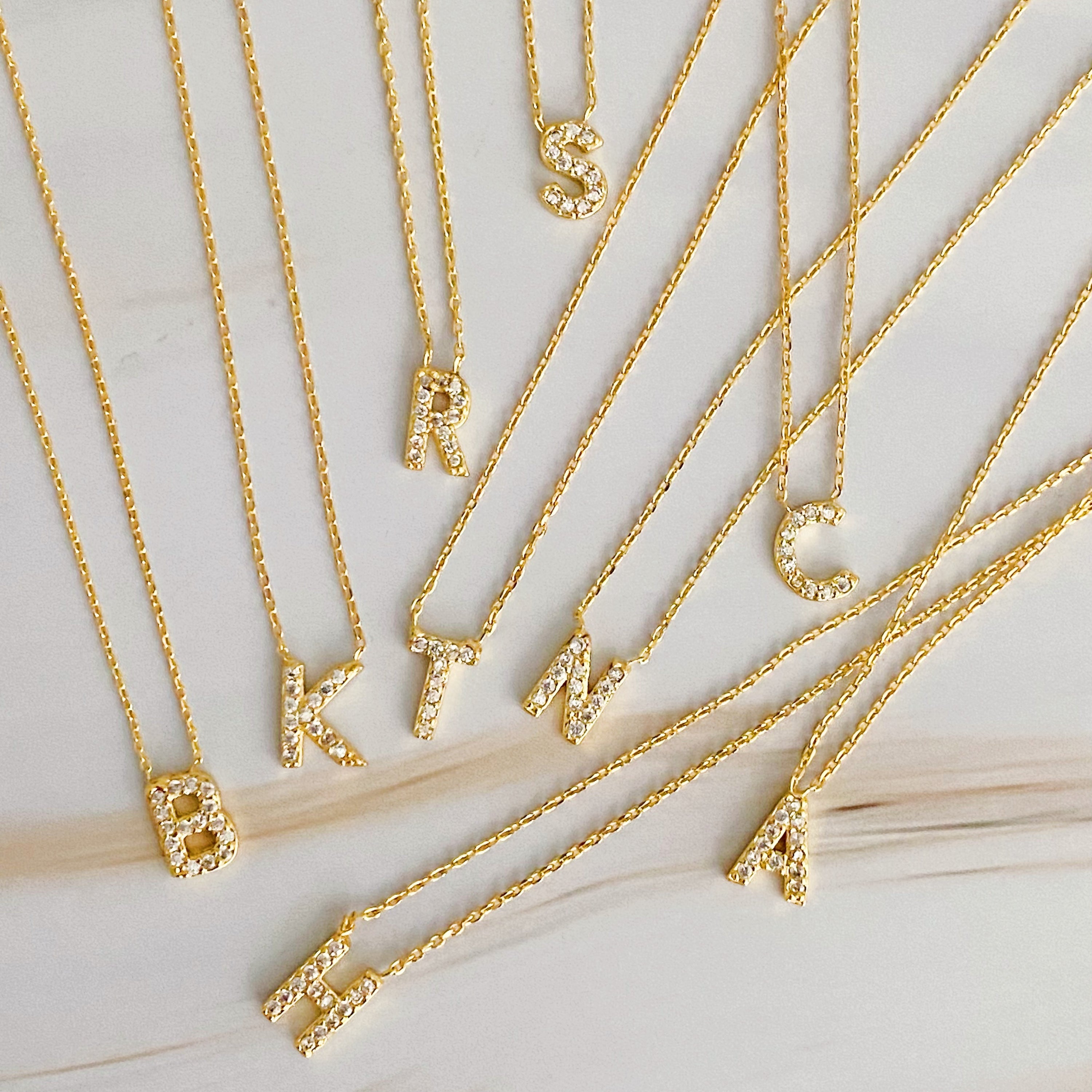 A delicate Understated Beauty Initial Necklace featuring a gold plated initial pendant adorned with sparkling cubic zirconia stones.