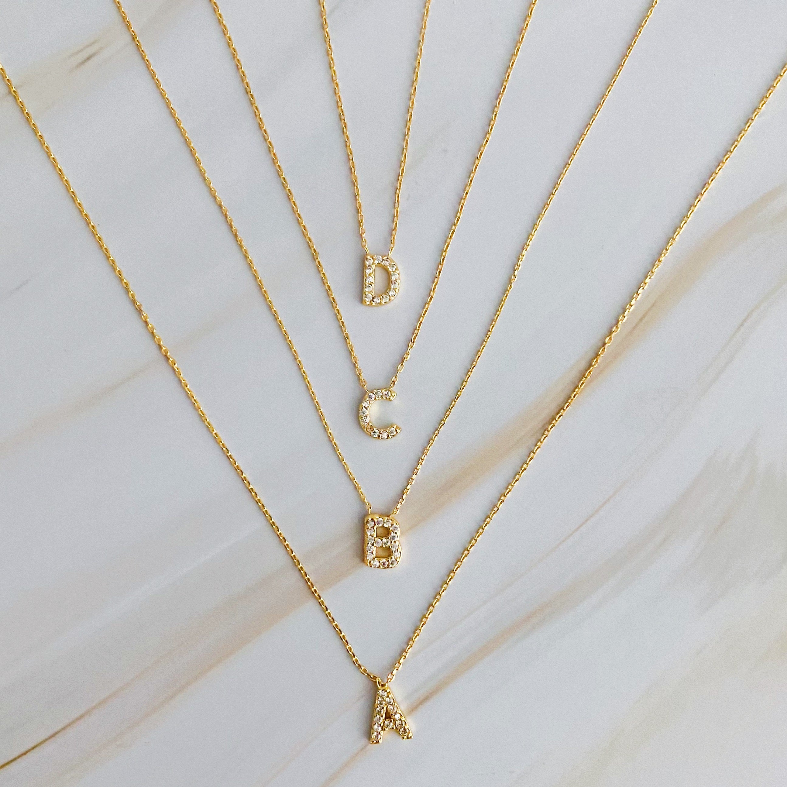 A delicate Understated Beauty Initial Necklace featuring a gold plated initial pendant adorned with sparkling cubic zirconia stones.