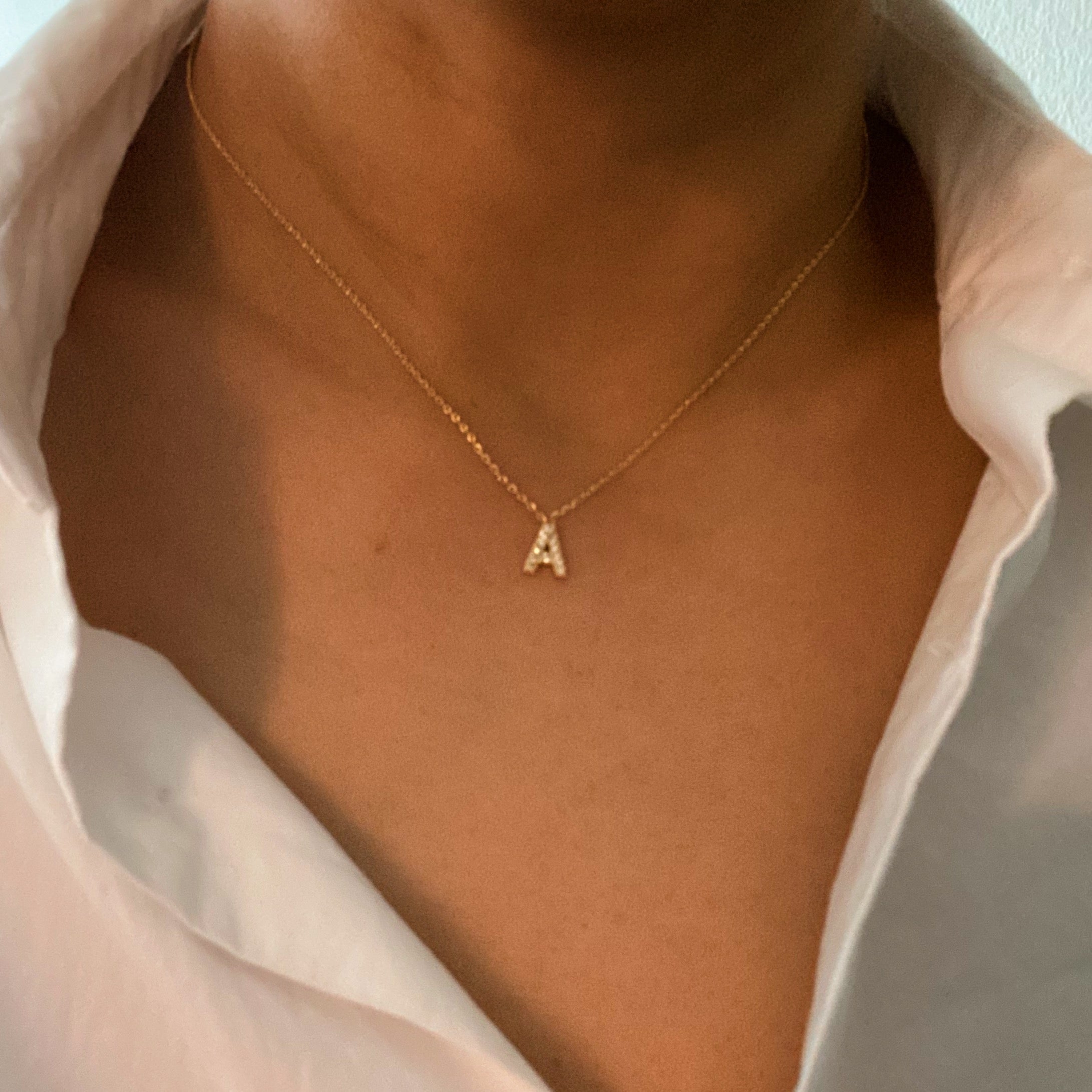 A delicate Understated Beauty Initial Necklace featuring a gold plated initial pendant adorned with sparkling cubic zirconia stones.