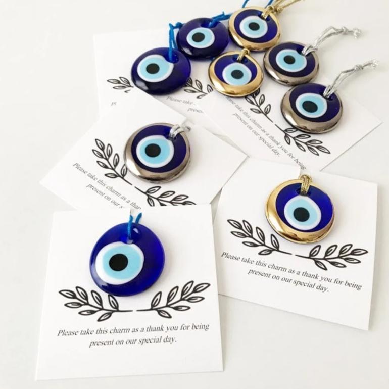 A collection of unique evil eye wedding favors featuring blue, gold, and silver beads, beautifully arranged with personalized cards.