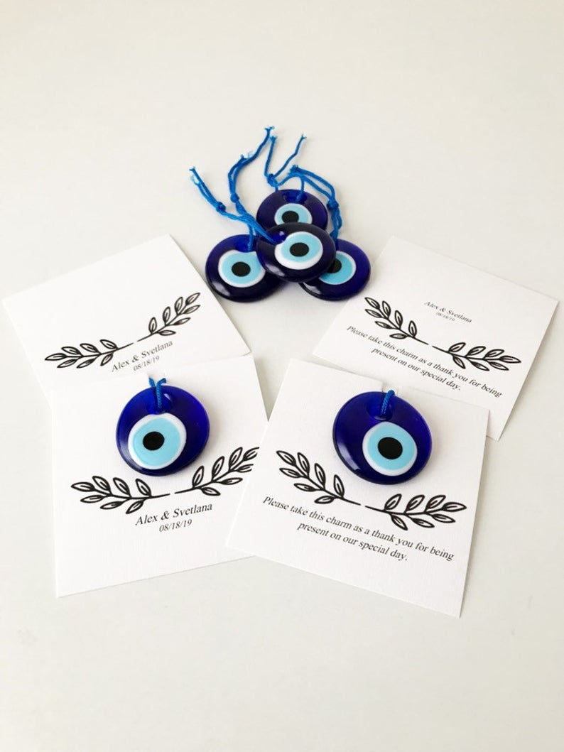 A collection of unique evil eye wedding favors featuring blue, gold, and silver beads, beautifully arranged with personalized cards.