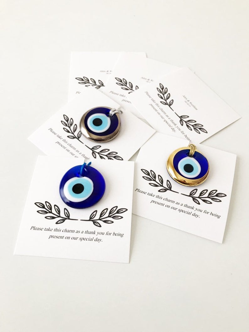 A collection of unique evil eye wedding favors featuring blue, gold, and silver beads, beautifully arranged with personalized cards.