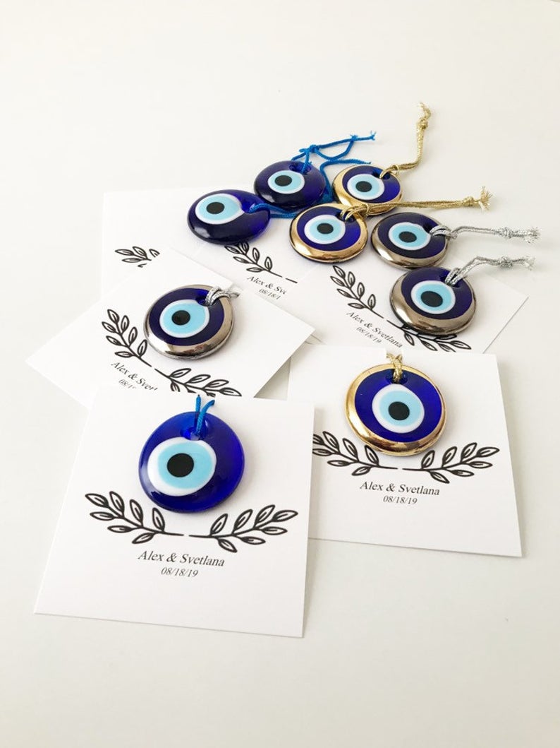 A collection of unique evil eye wedding favors featuring blue, gold, and silver beads, beautifully arranged with personalized cards.