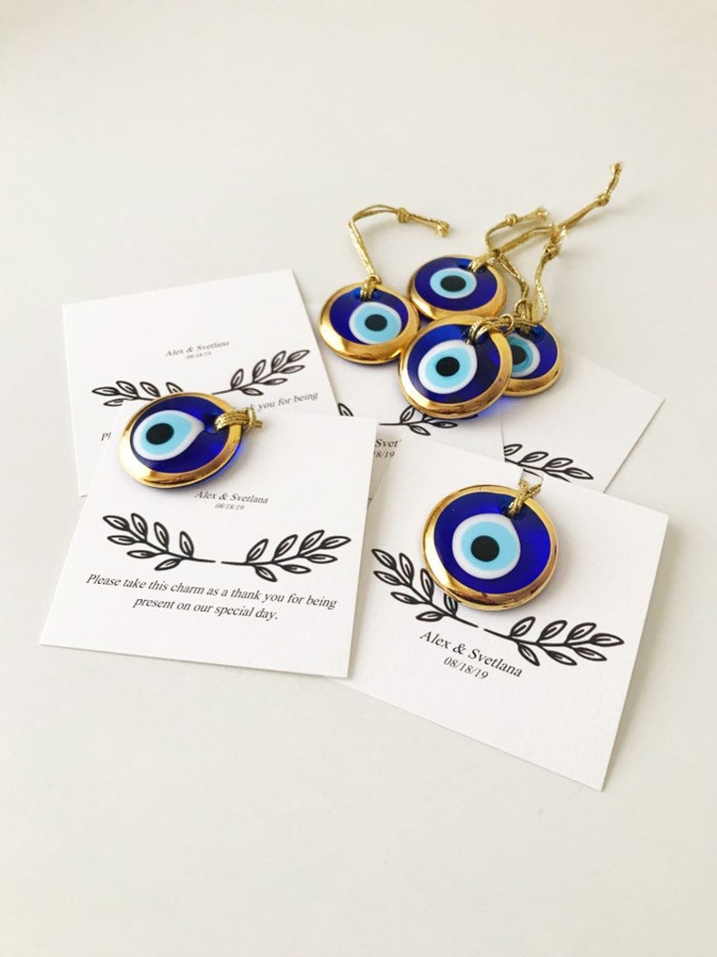 A collection of unique evil eye wedding favors featuring blue, gold, and silver beads, beautifully arranged with personalized cards.