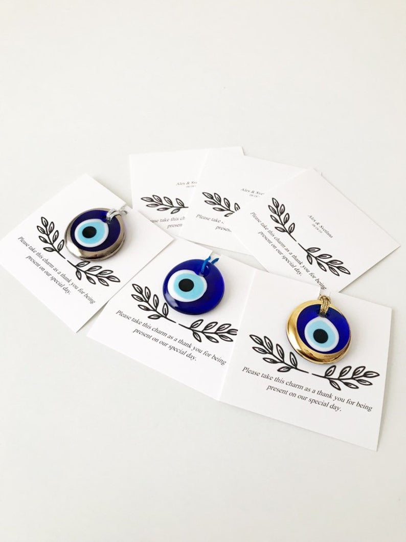 A collection of unique evil eye wedding favors featuring blue, gold, and silver beads, beautifully arranged with personalized cards.