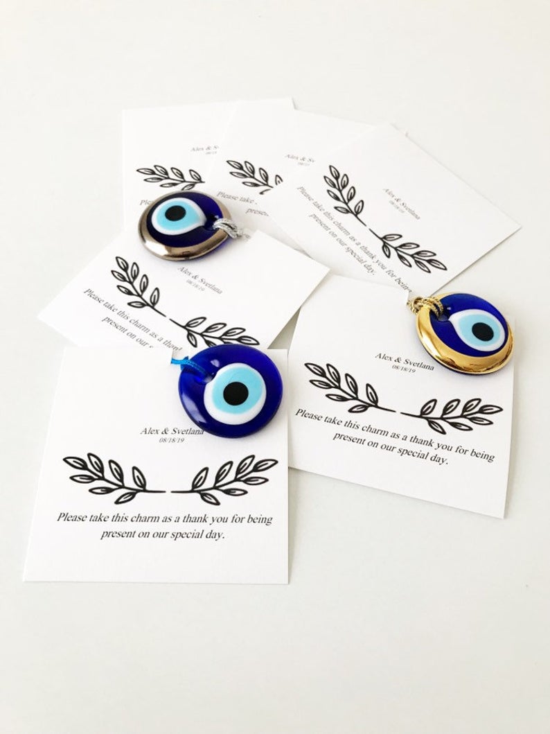 A collection of unique evil eye wedding favors featuring blue, gold, and silver beads, beautifully arranged with personalized cards.