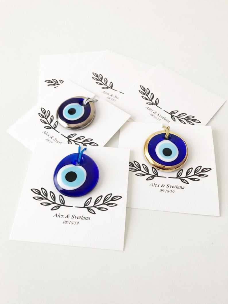 A collection of unique evil eye wedding favors featuring blue, gold, and silver beads, beautifully arranged with personalized cards.