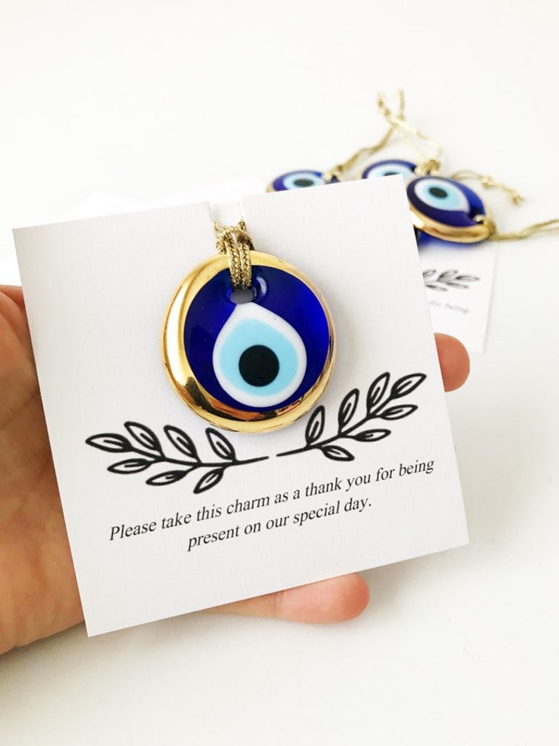 A collection of unique evil eye wedding favors featuring blue, gold, and silver beads, beautifully arranged with personalized cards.