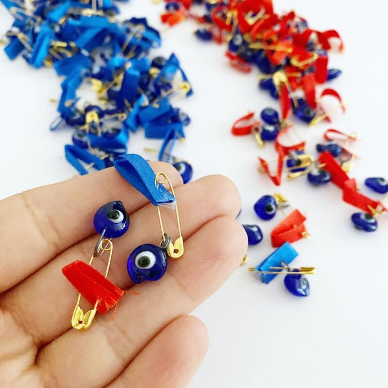 A collection of unique evil eye safety pins adorned with colorful glass beads and ribbons, perfect for wedding favors.