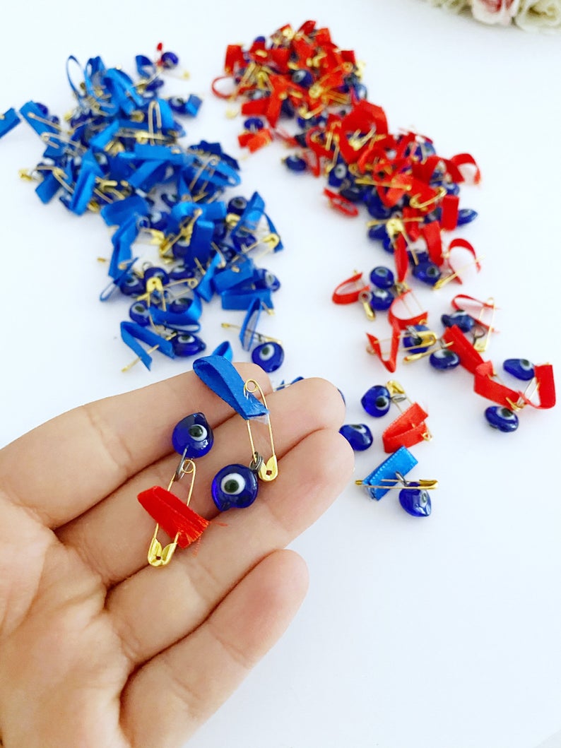 A collection of unique evil eye safety pins adorned with colorful glass beads and ribbons, perfect for wedding favors.