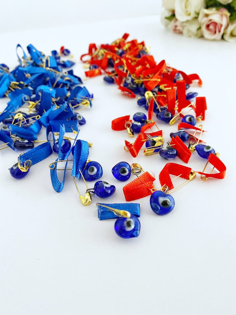 A collection of unique evil eye safety pins adorned with colorful glass beads and ribbons, perfect for wedding favors.