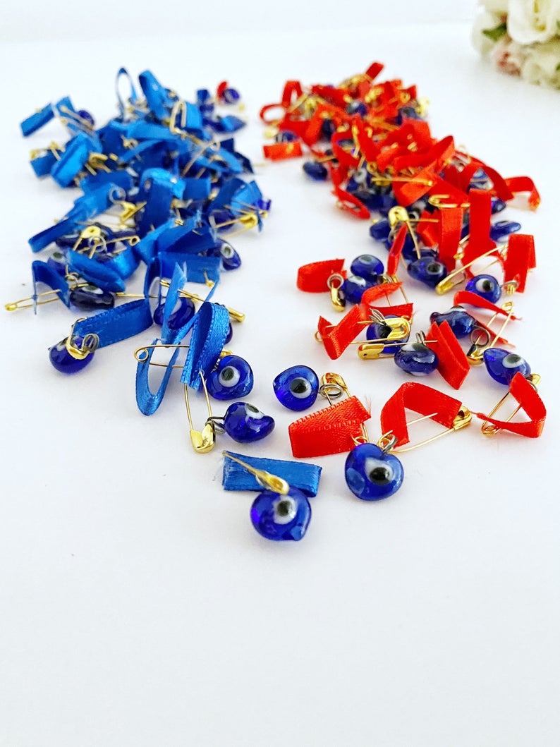 A collection of unique evil eye safety pins adorned with colorful glass beads and ribbons, perfect for wedding favors.