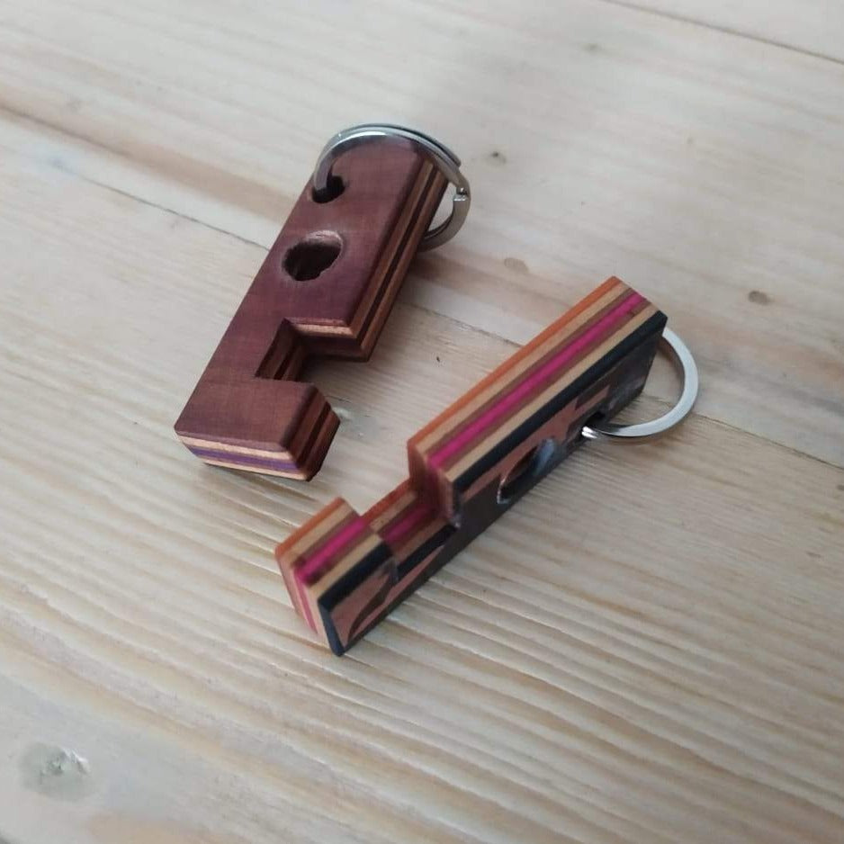 Upcycled Skateboard Mobile & Earphone Holder Keyring showcasing vibrant colors and unique patterns, designed for multifunctional use.