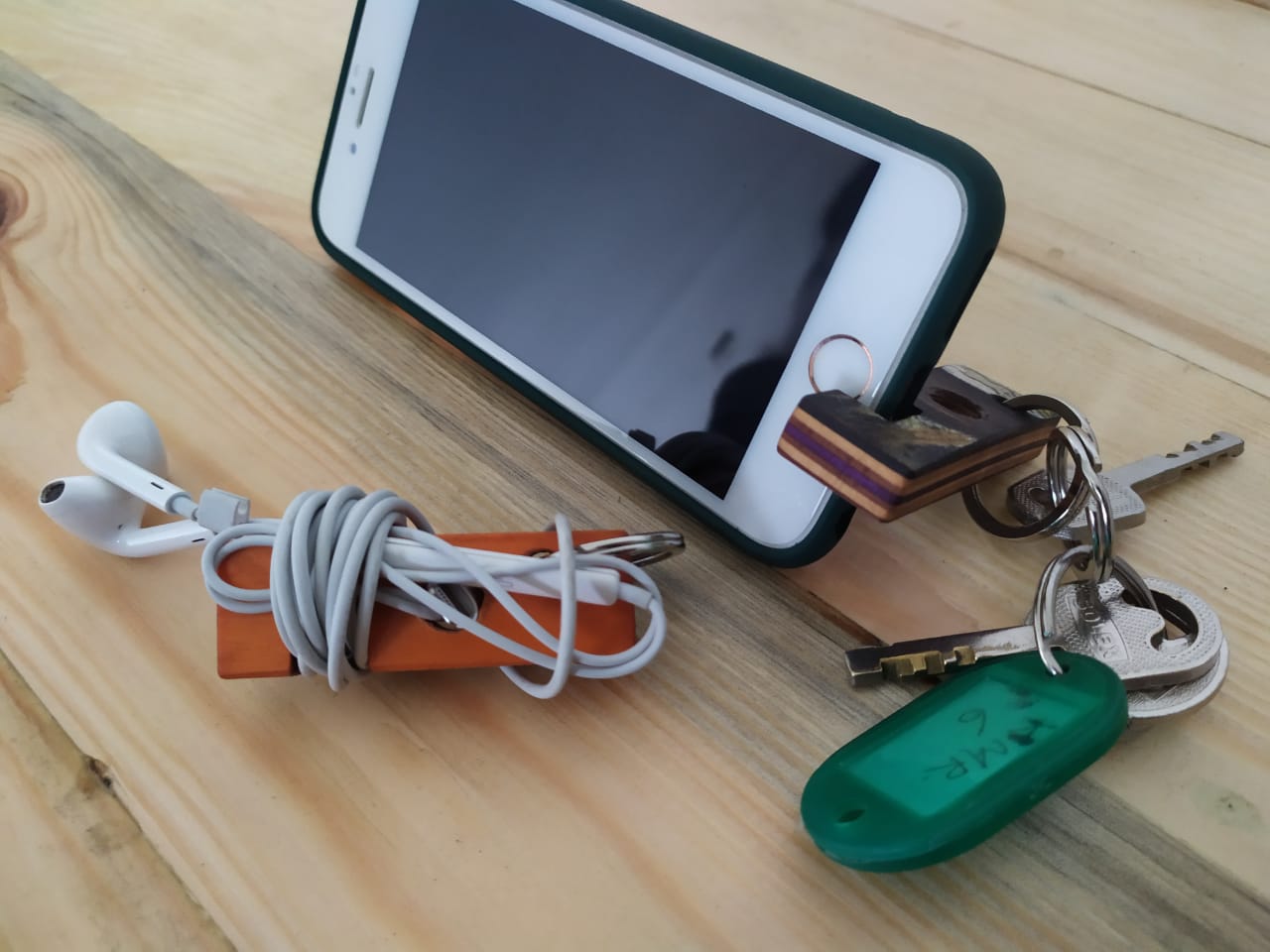 Upcycled Skateboard Mobile & Earphone Holder Keyring showcasing vibrant colors and unique patterns, designed for multifunctional use.