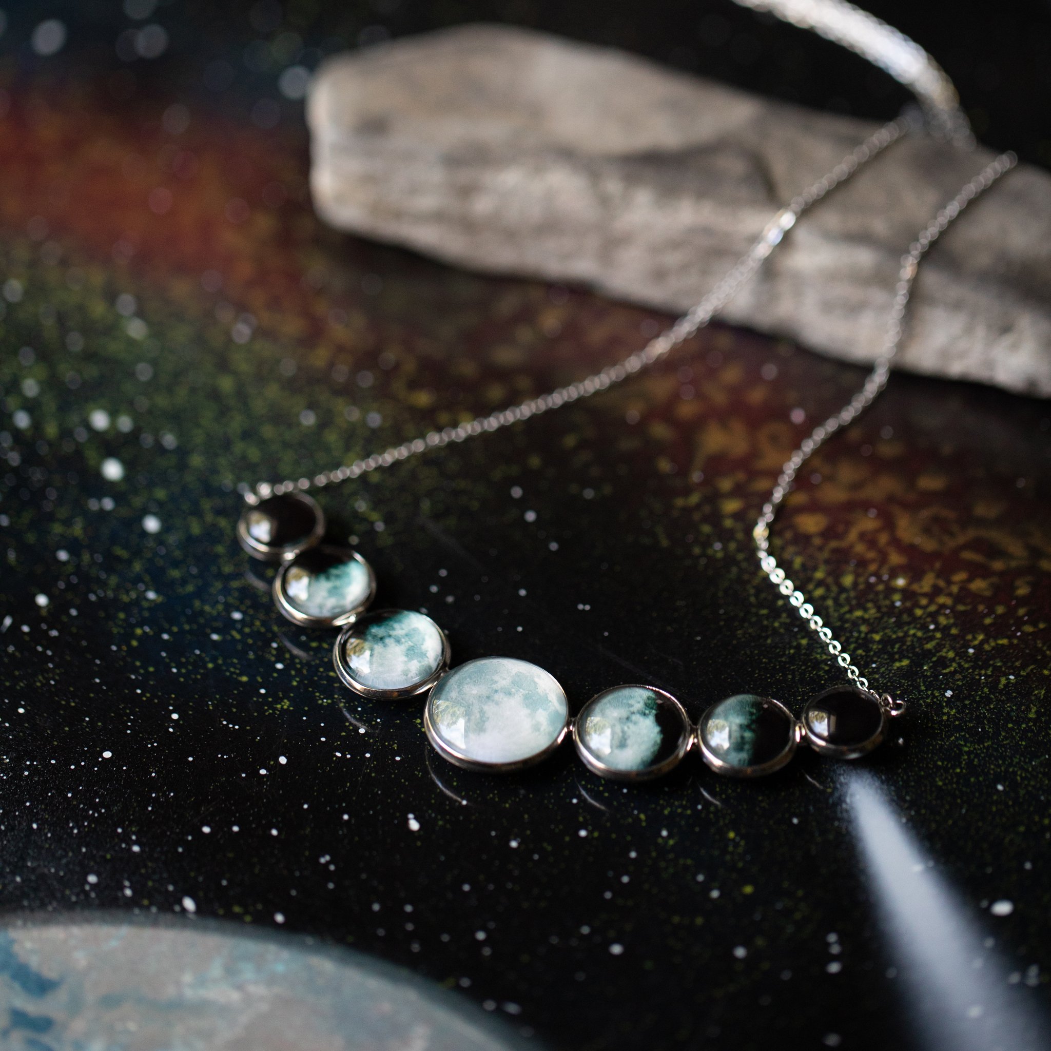 Varying Sized Curved Moon Phase Necklace in Silver showcasing seven distinct moon phases in handcrafted silver bezels.