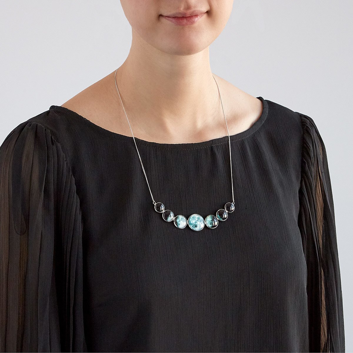 Varying Sized Curved Moon Phase Necklace in Silver showcasing seven distinct moon phases in handcrafted silver bezels.