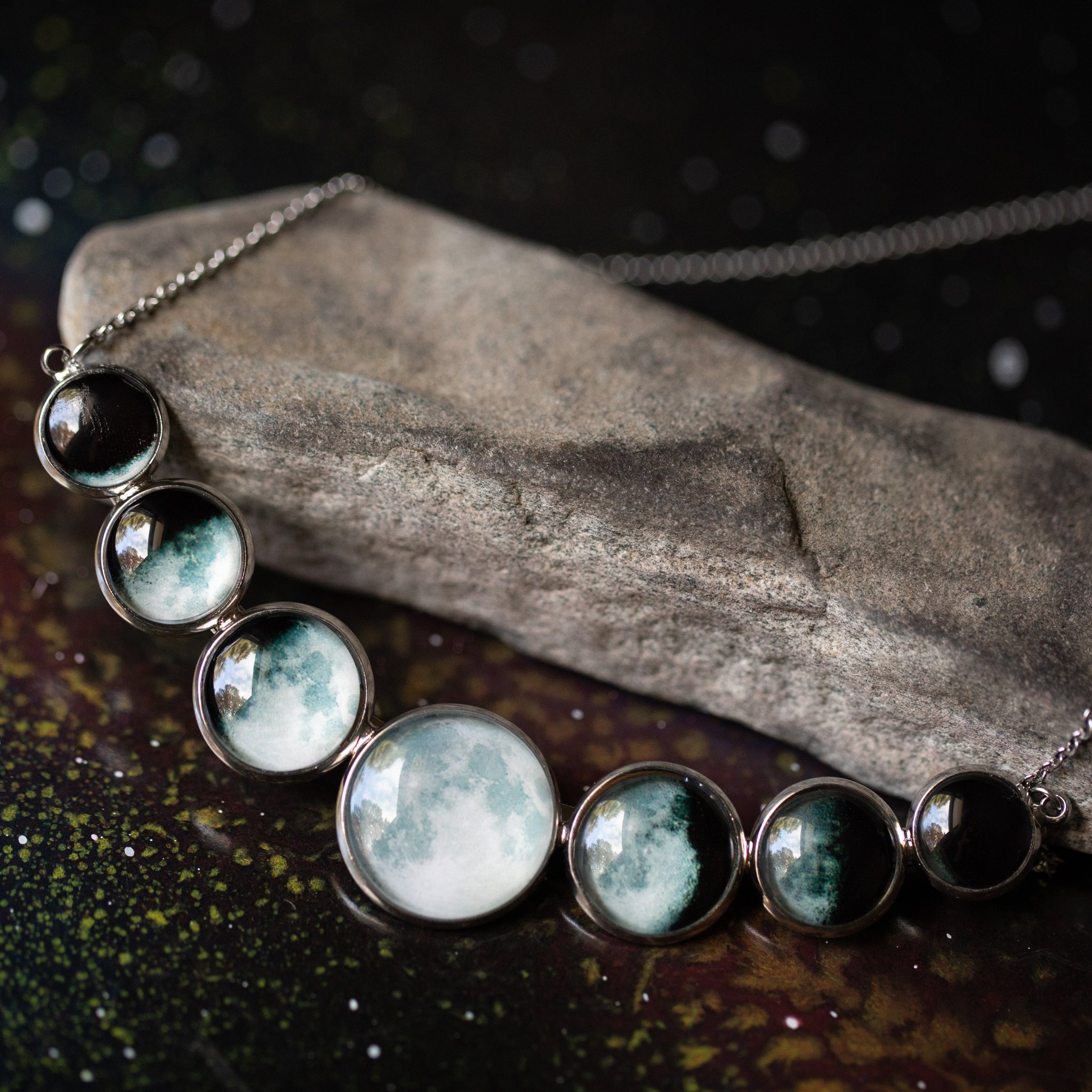 Varying Sized Curved Moon Phase Necklace in Silver showcasing seven distinct moon phases in handcrafted silver bezels.