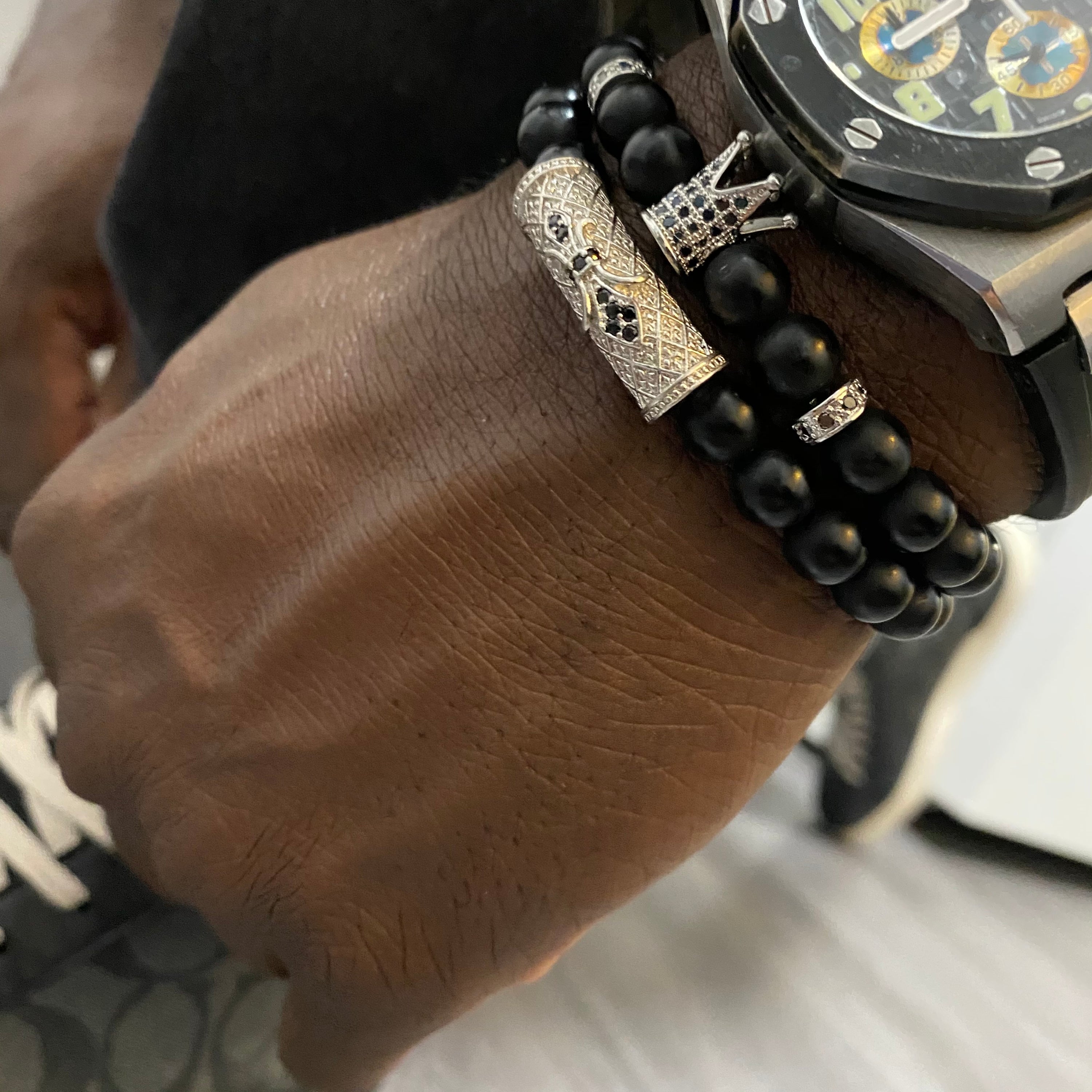 Vortex Bracelet Set featuring two black onyx bracelets with zirconia spacers and royal crown beads, available in four metal colors.