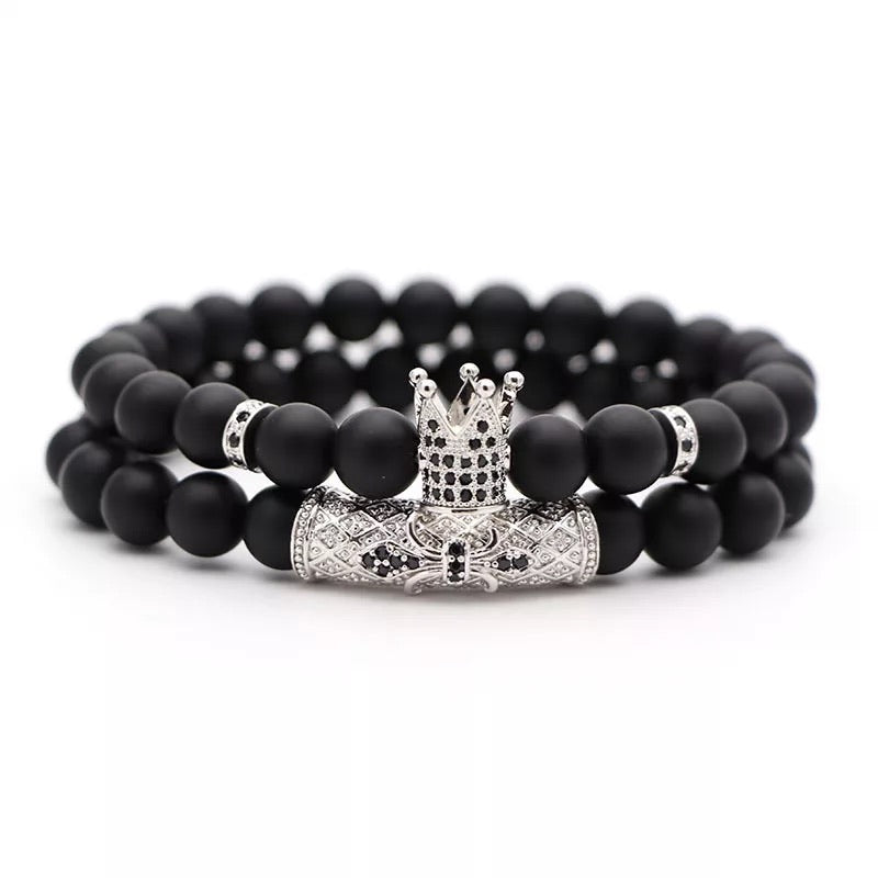 Vortex Bracelet Set featuring two black onyx bracelets with zirconia spacers and royal crown beads, available in four metal colors.