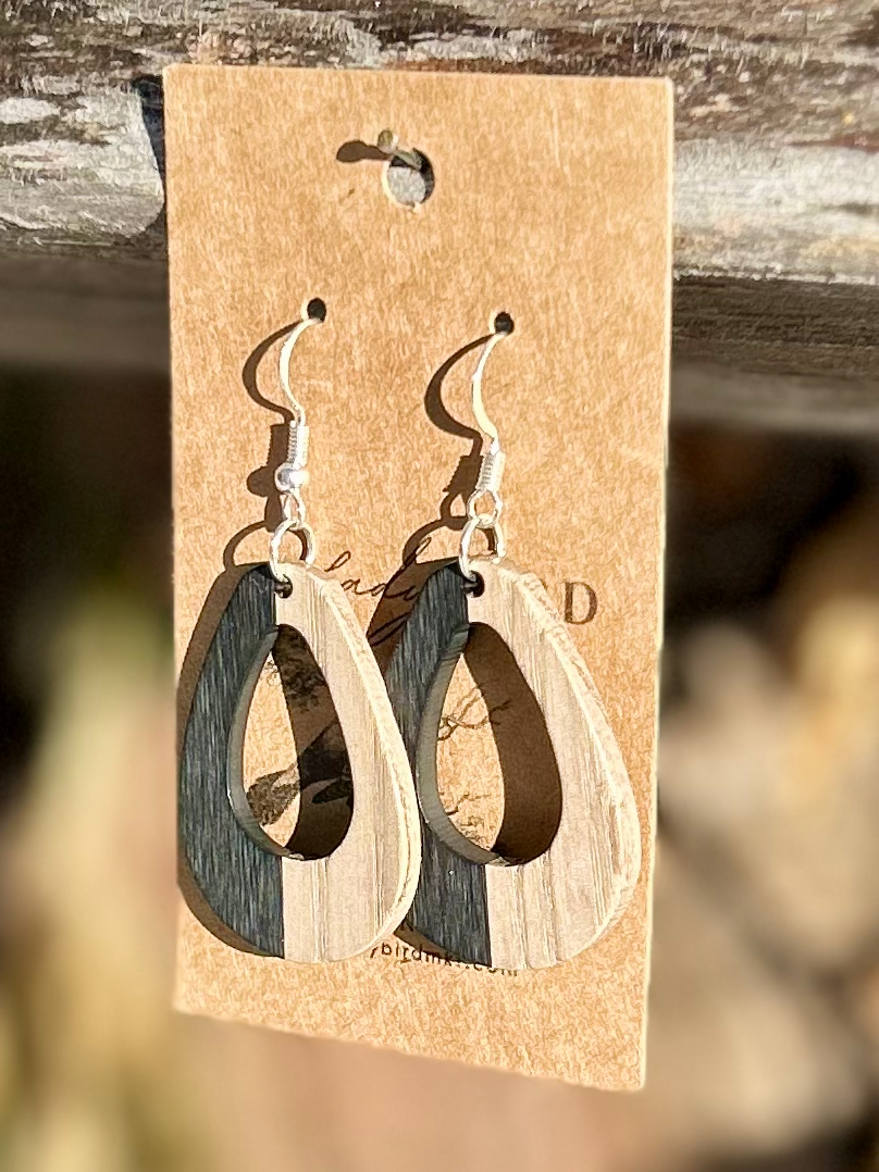 A pair of oval hoop earrings made from walnut wood and black resin, showcasing unique wood grain patterns and a modern design.