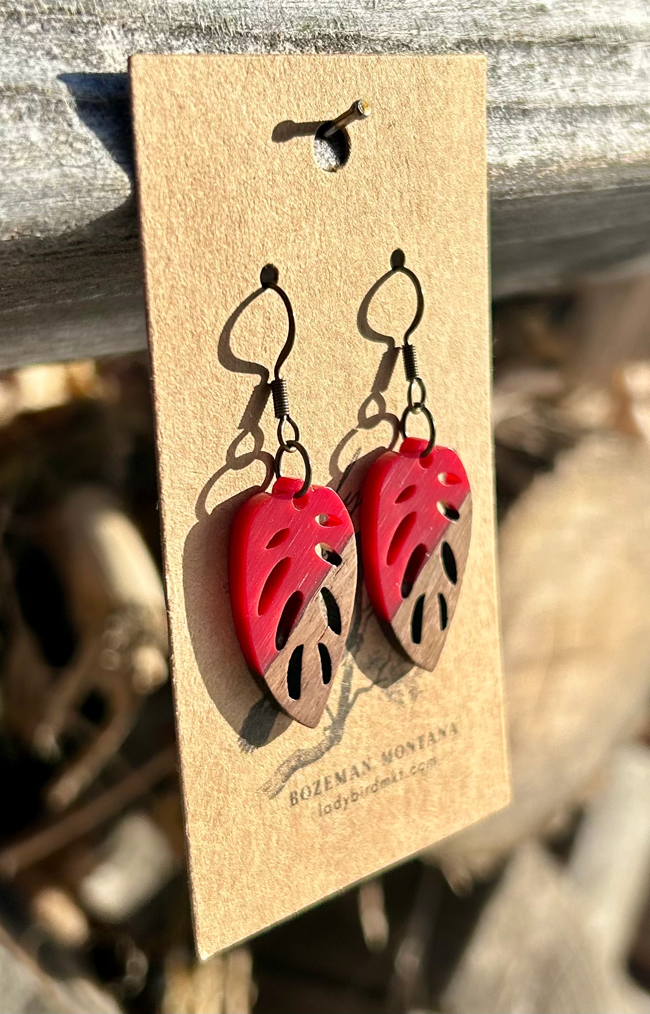 Walnut wood and bright red resin leaf earrings showcasing unique grain patterns and vibrant color.