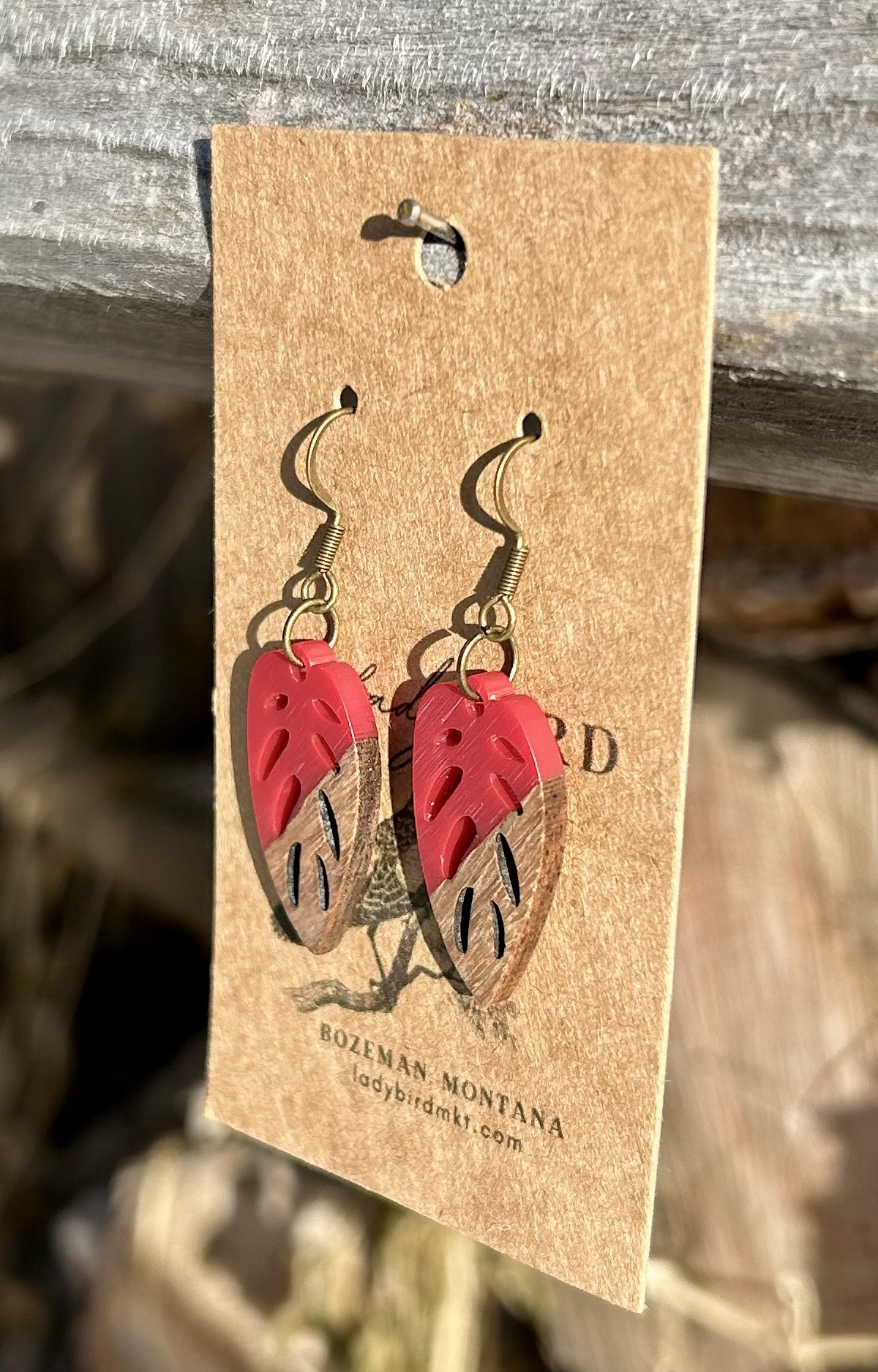 Walnut wood and bright red resin leaf earrings showcasing unique grain patterns and vibrant color.