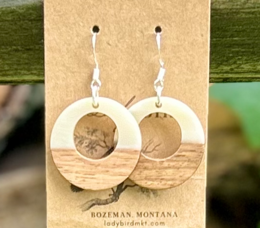 A pair of lightweight hoop earrings made from walnut wood and pearly white resin, showcasing unique wood grain patterns.