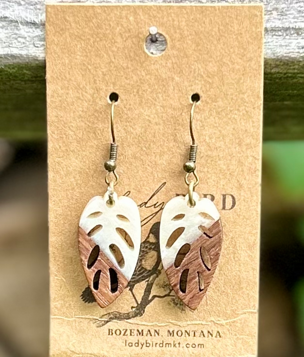 A pair of leaf-shaped earrings made from walnut wood and pearly white resin, showcasing natural wood grain and elegant design.