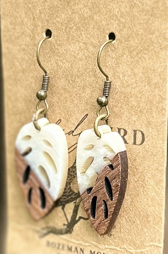 A pair of leaf-shaped earrings made from walnut wood and pearly white resin, showcasing natural wood grain and elegant design.