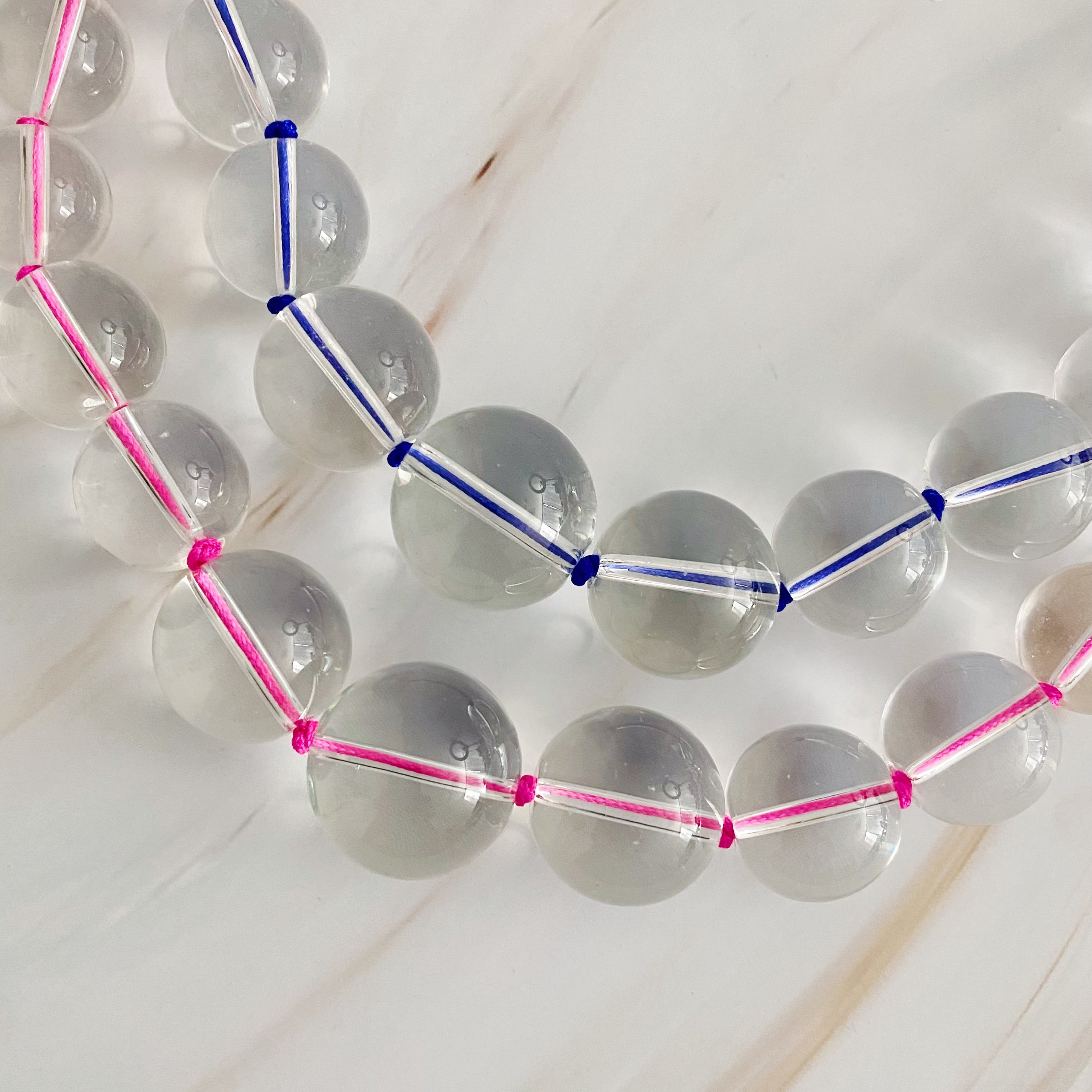 A vibrant Water Stone Knotted In Color Necklace featuring graduated clear ball beads and colorful hand-knotted threads, perfect for any occasion.