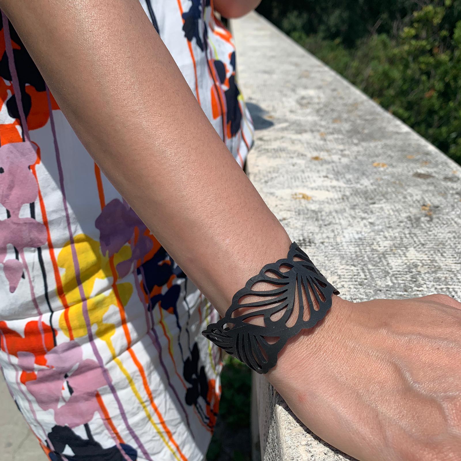 A stylish Weave Recycled Inner Tube Bracelet made from reclaimed rubber, showcasing intricate hand-woven patterns and a plastic button clasp.