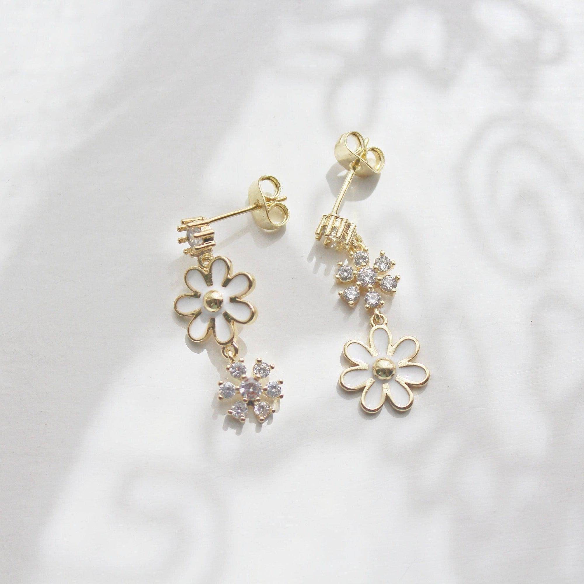 A pair of White Daisy Earrings featuring mismatched designs with sterling silver studs and gold plated bronze bodies, elegantly displayed in a gift box.