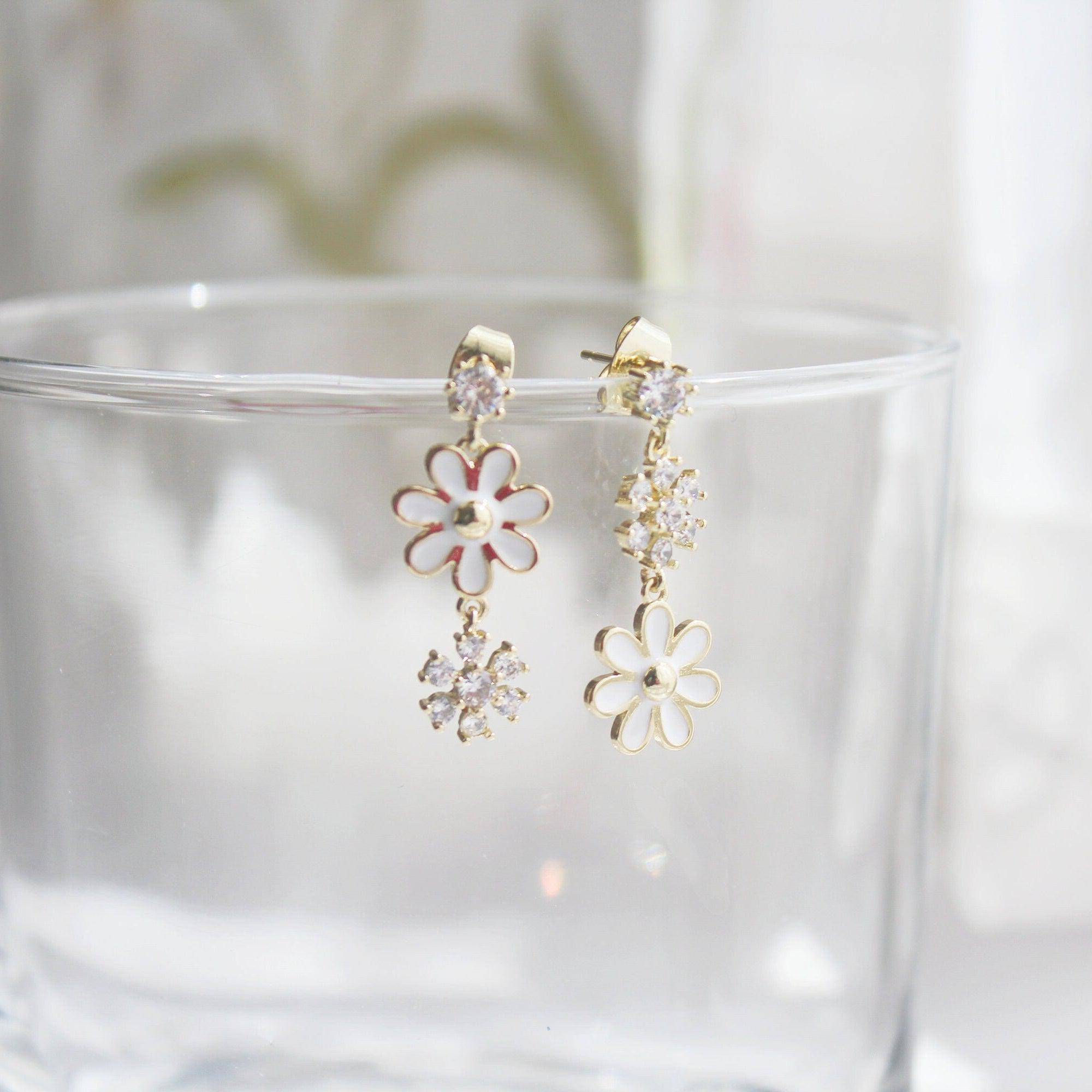 A pair of White Daisy Earrings featuring mismatched designs with sterling silver studs and gold plated bronze bodies, elegantly displayed in a gift box.