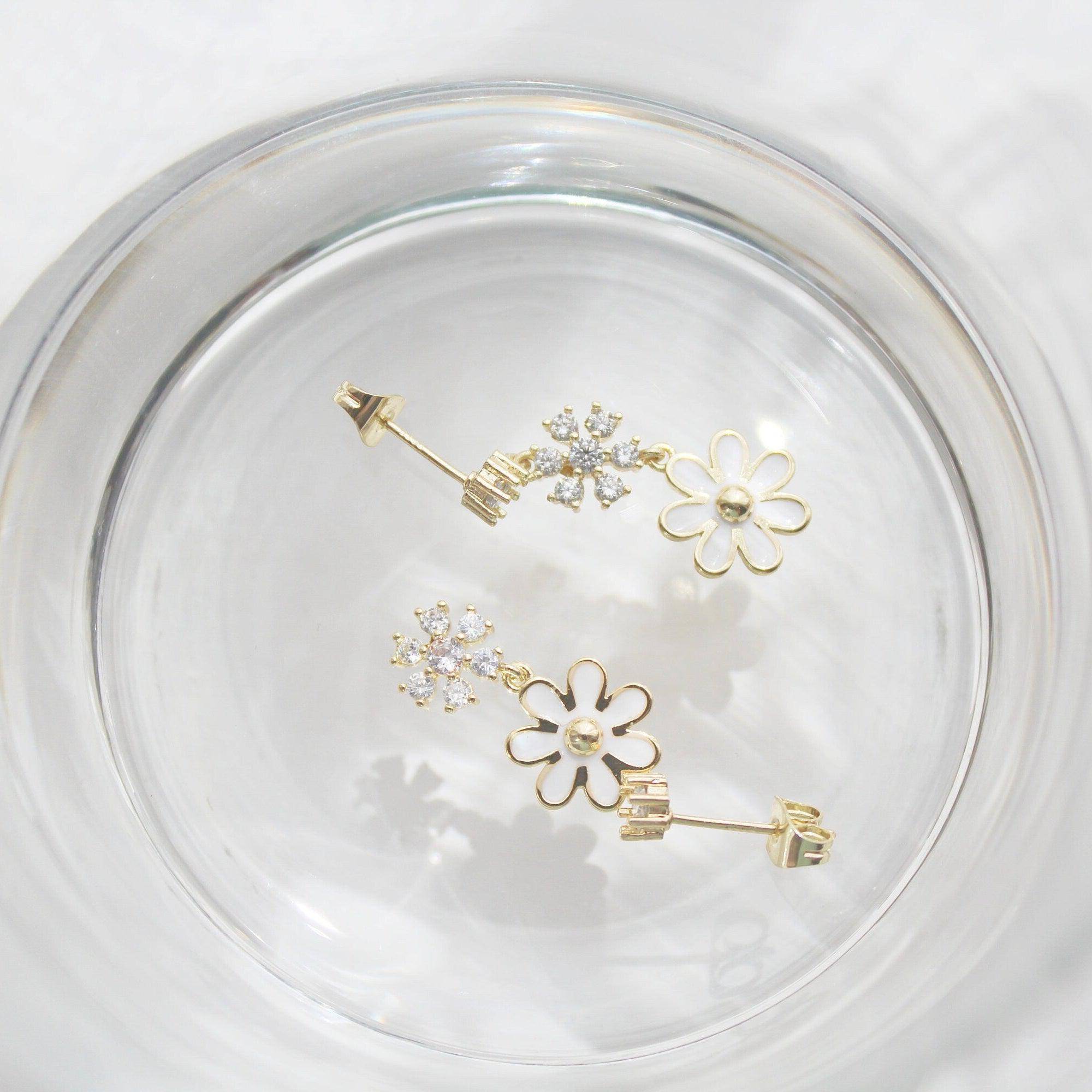 A pair of White Daisy Earrings featuring mismatched designs with sterling silver studs and gold plated bronze bodies, elegantly displayed in a gift box.