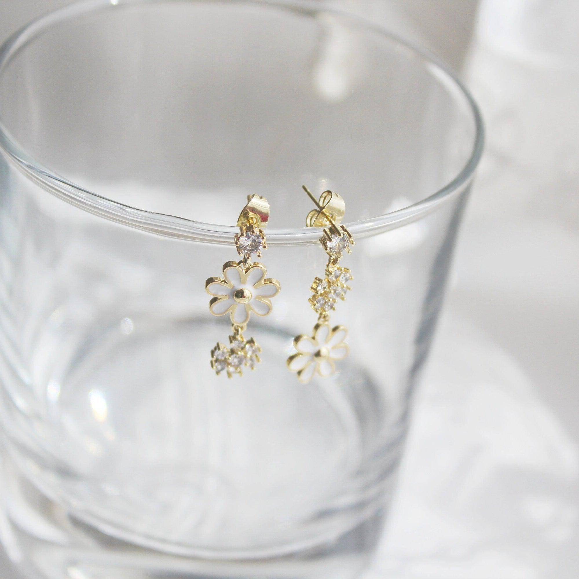 A pair of White Daisy Earrings featuring mismatched designs with sterling silver studs and gold plated bronze bodies, elegantly displayed in a gift box.