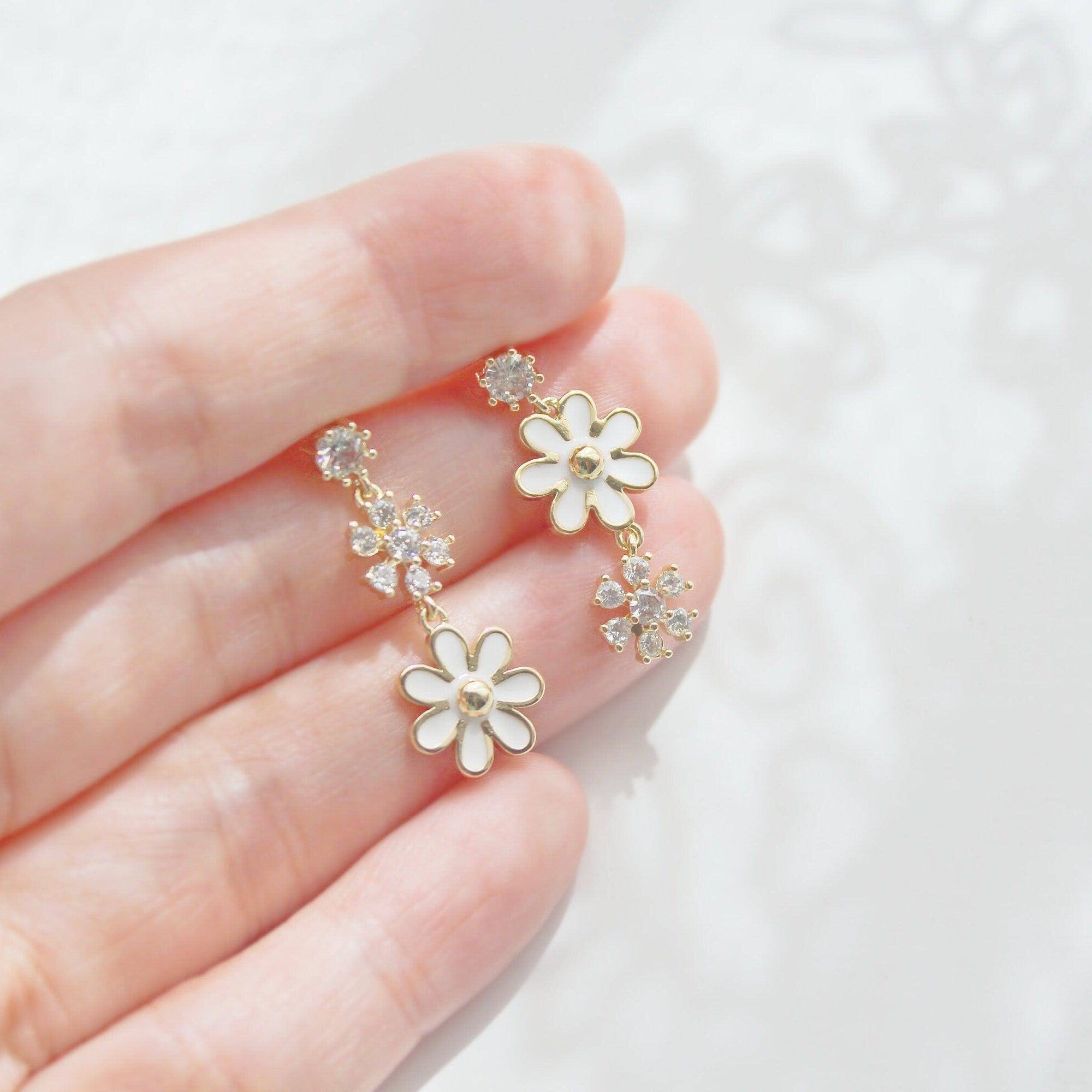 A pair of White Daisy Earrings featuring mismatched designs with sterling silver studs and gold plated bronze bodies, elegantly displayed in a gift box.