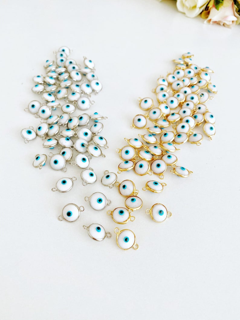 A collection of White Evil Eye Beads featuring gold and silver finishes, ideal for jewelry making.