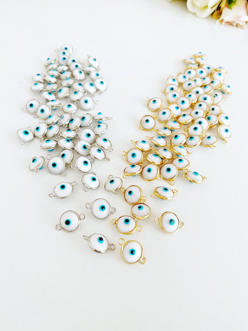 A collection of White Evil Eye Beads featuring gold and silver finishes, ideal for jewelry making.