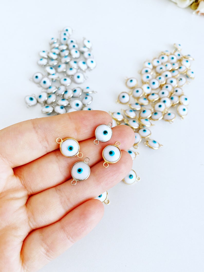 A collection of White Evil Eye Beads featuring gold and silver finishes, ideal for jewelry making.