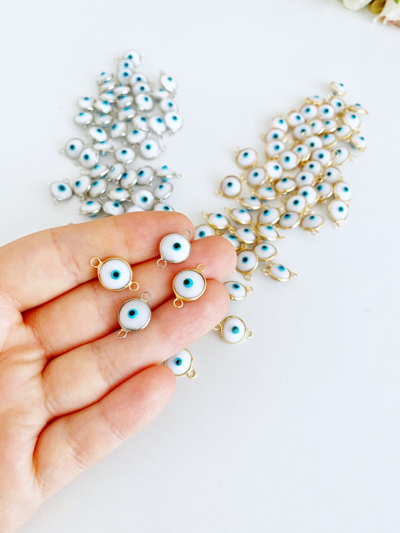 A collection of White Evil Eye Beads featuring gold and silver finishes, ideal for jewelry making.