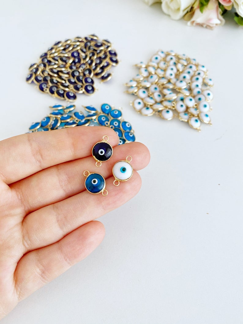 A collection of White Evil Eye Beads featuring gold and silver finishes, ideal for jewelry making.