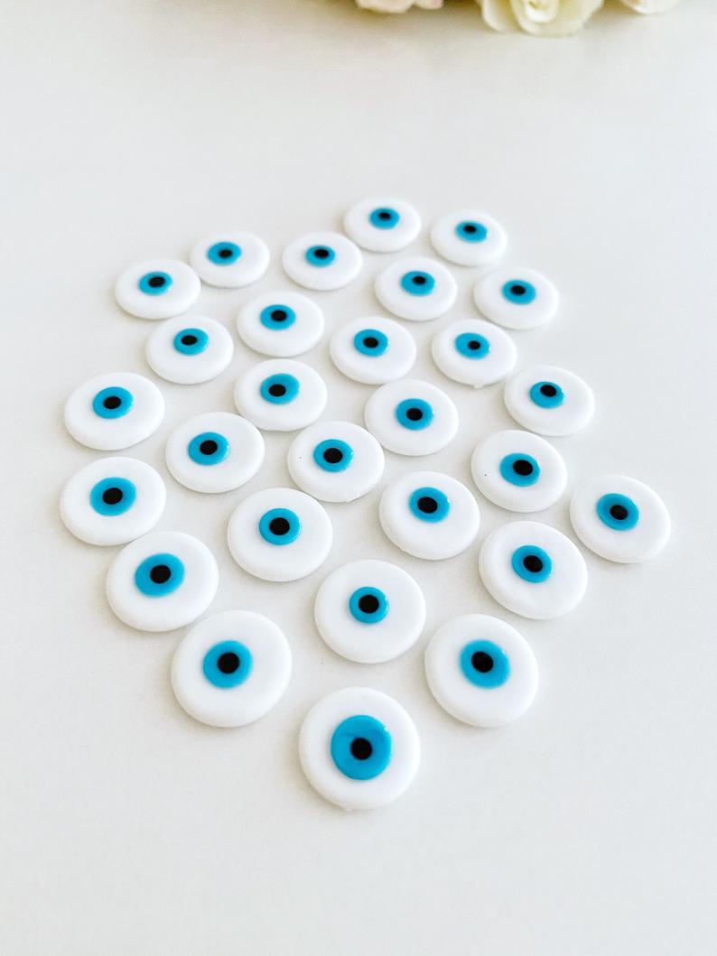 A collection of white evil eye cabochons made from Murano glass, showcasing their round shape and unique design.