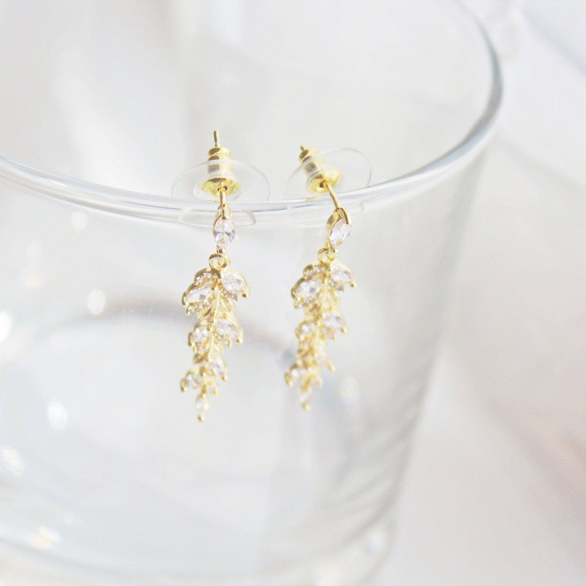 Elegant gold and crystal leaf dangle drop earrings, showcasing a beautiful design that embodies grace and sophistication.