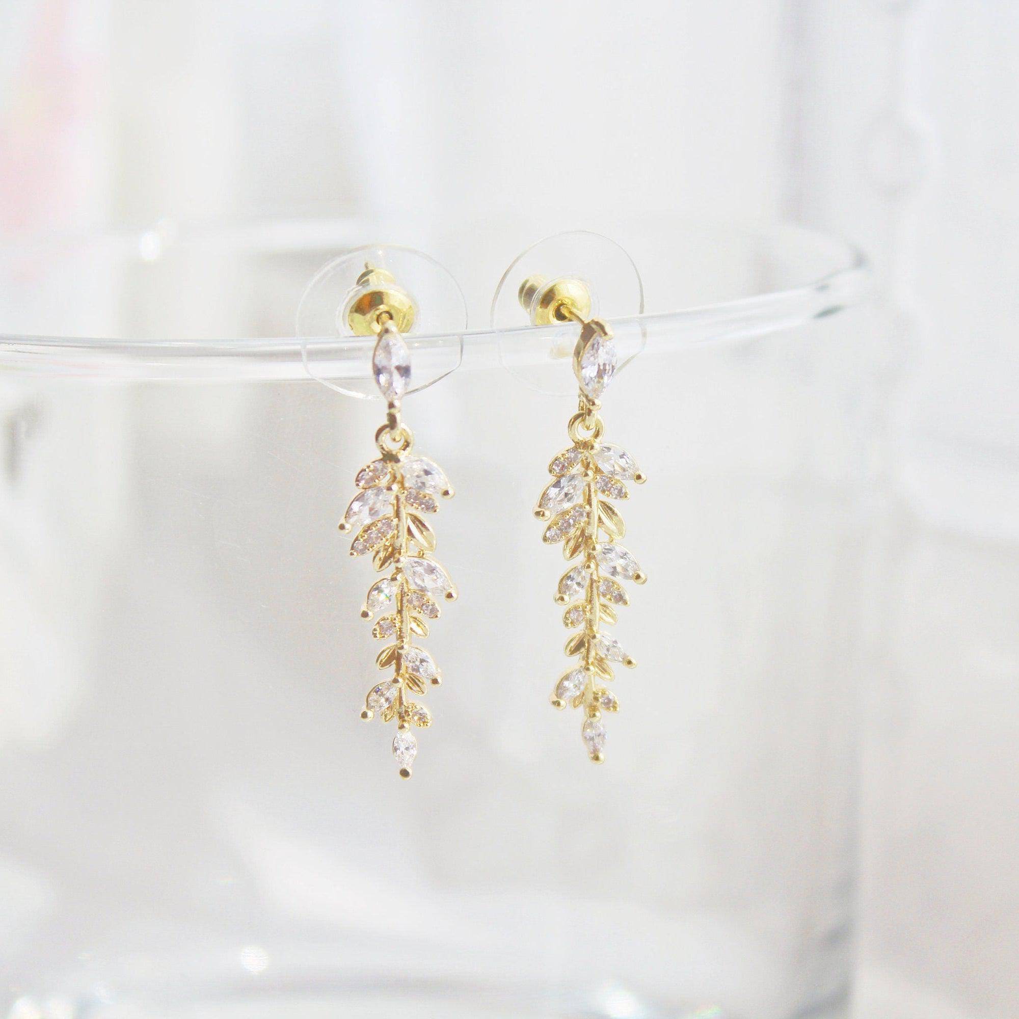 Elegant gold and crystal leaf dangle drop earrings, showcasing a beautiful design that embodies grace and sophistication.