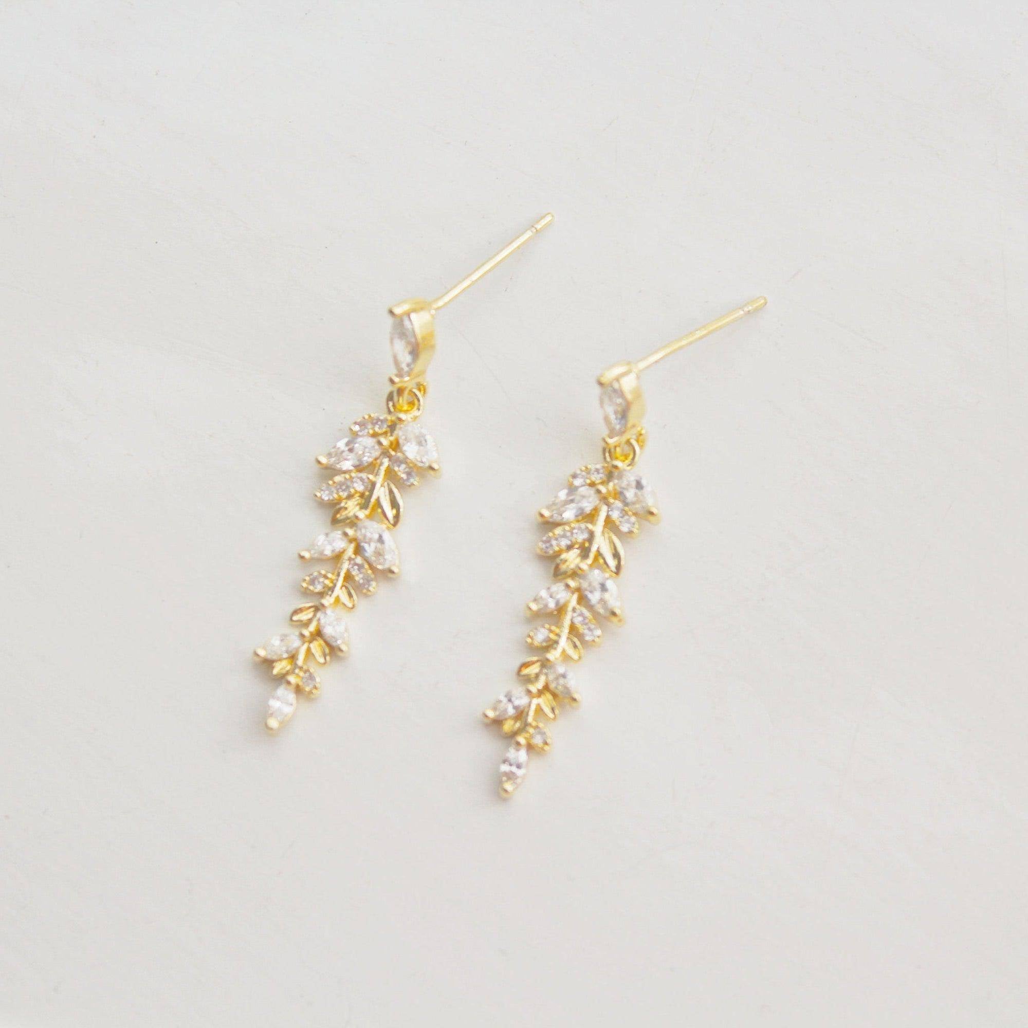 Elegant gold and crystal leaf dangle drop earrings, showcasing a beautiful design that embodies grace and sophistication.