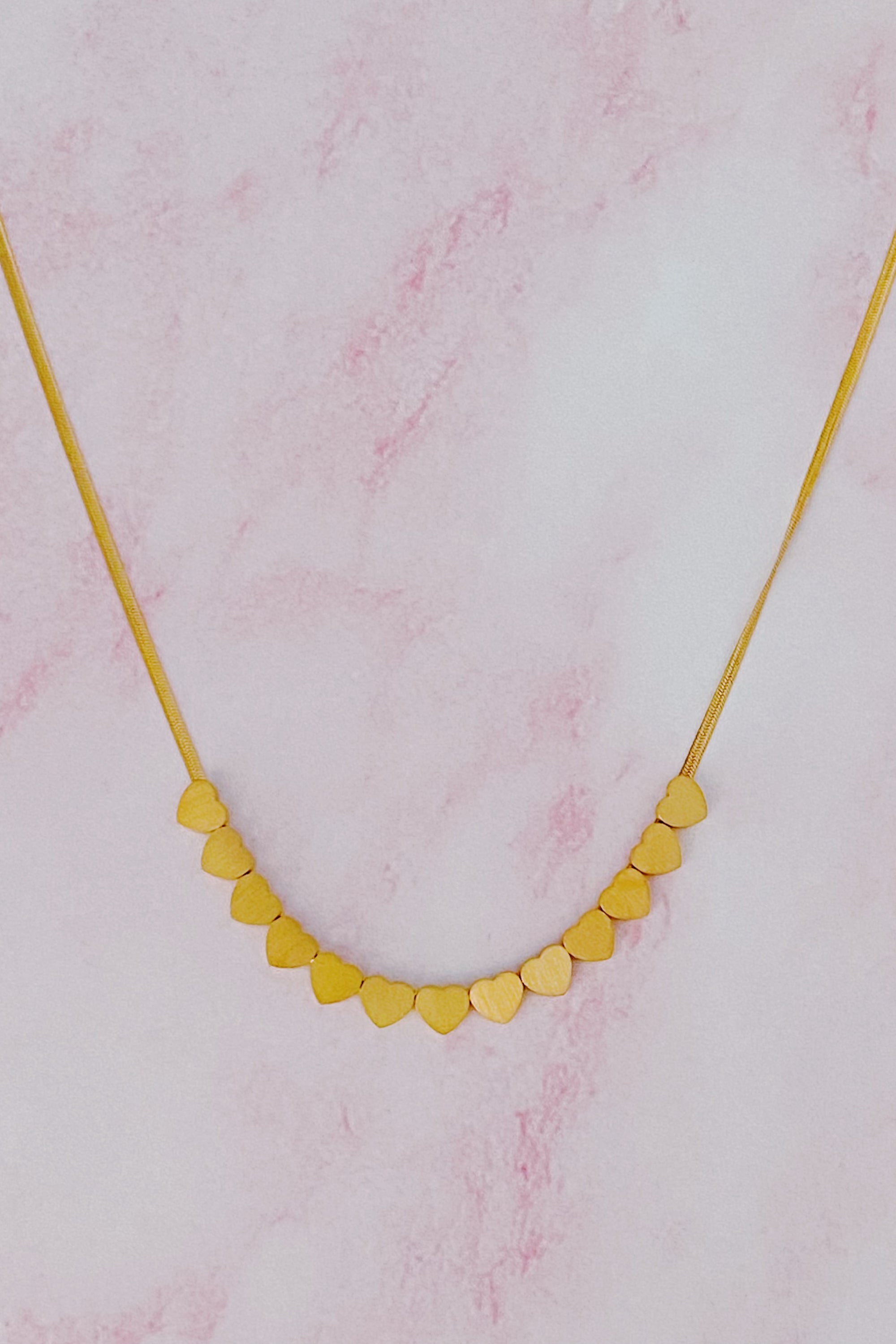 With Me Mini Hearts Necklace featuring small joined hearts, 18k gold plated stainless steel with a matte finish.