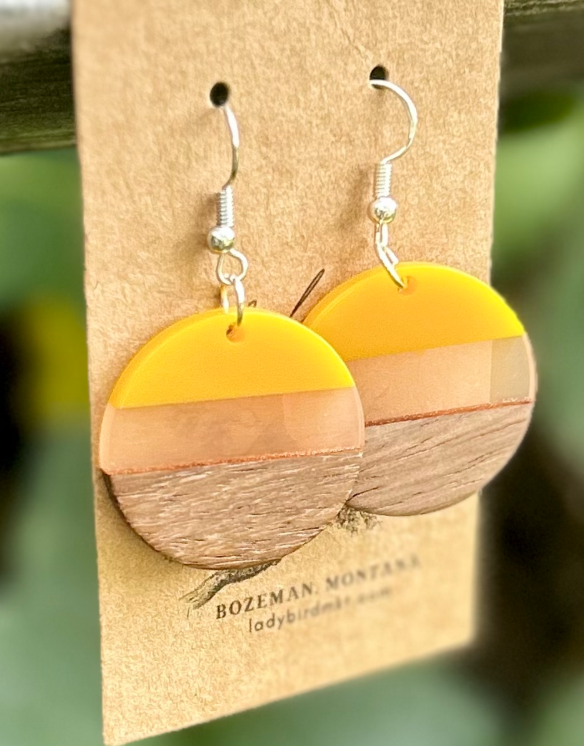 Wood and yellow mixed resin circle earrings with a translucent center stripe, showcasing natural wood grain.