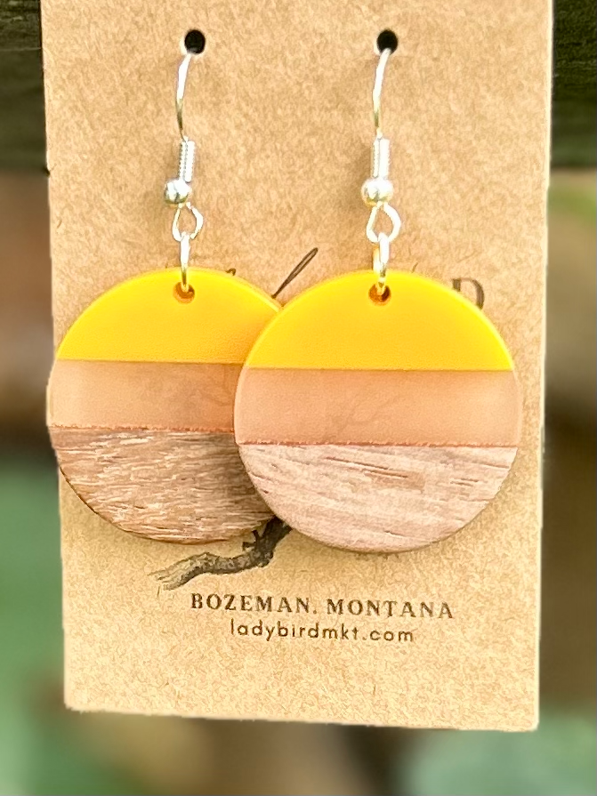 Wood and yellow mixed resin circle earrings with a translucent center stripe, showcasing natural wood grain.