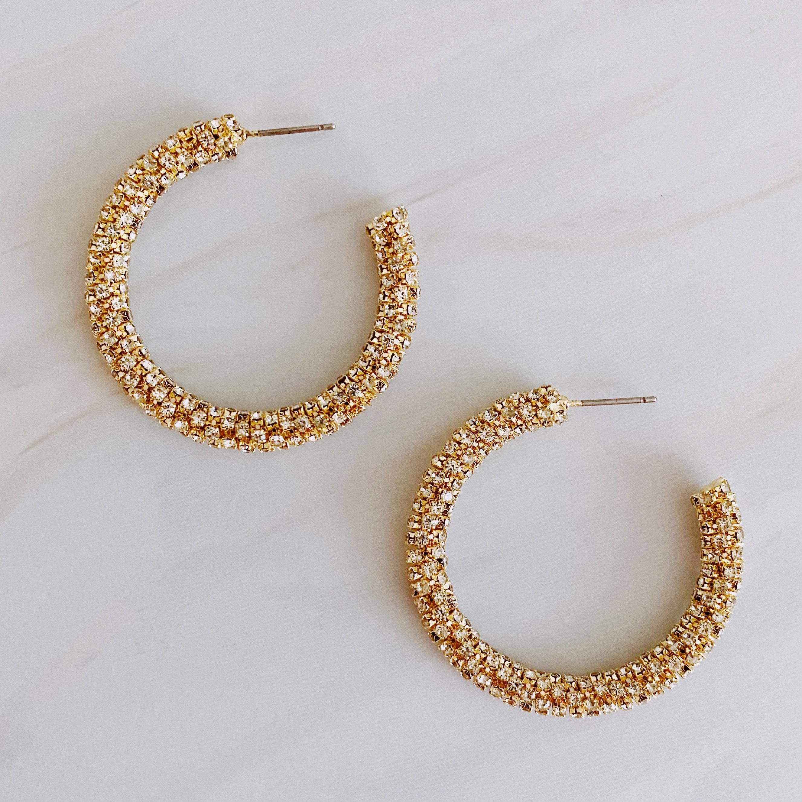 A pair of Wrapped In Shine Hoop Earrings featuring sparkling crystals on a classic hoop design, showcasing elegance and style.