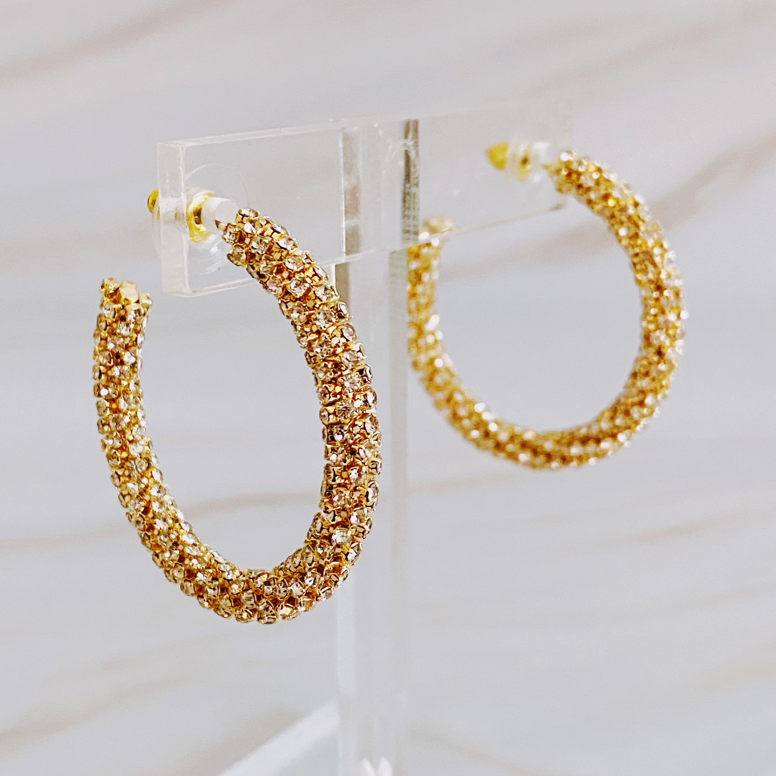 A pair of Wrapped In Shine Hoop Earrings featuring sparkling crystals on a classic hoop design, showcasing elegance and style.